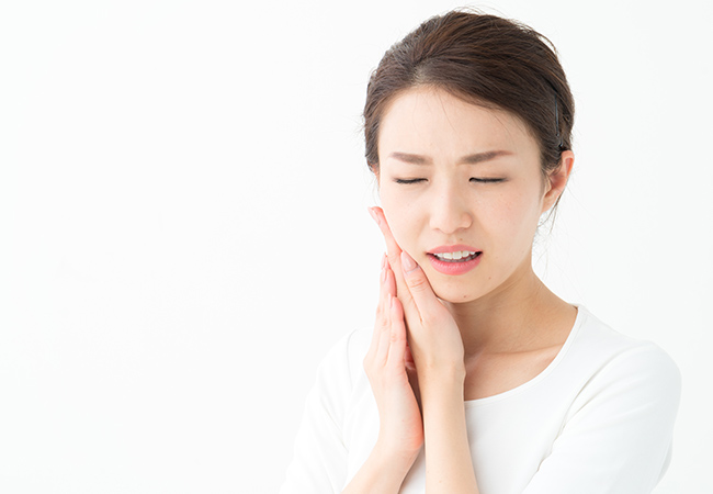 歯の痛みで顎に手を当てる女性